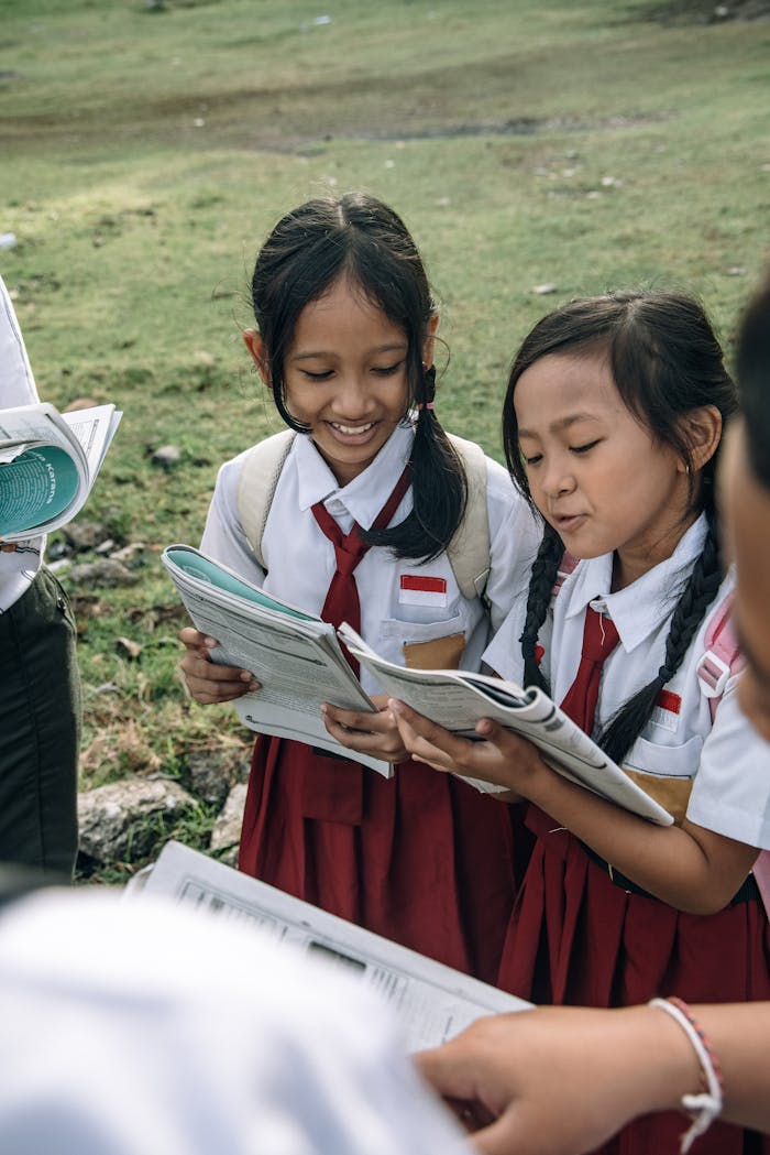 about-us Two smiling children in school uniforms reading books outdoors, enjoying learning together.