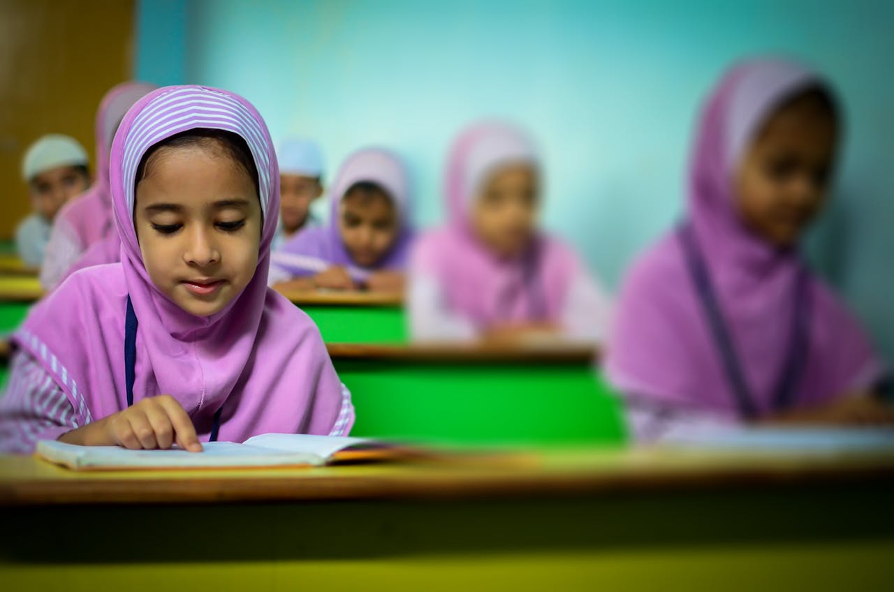 who-we-are Group of young students in traditional hijabs focusing on their studies in a classroom.