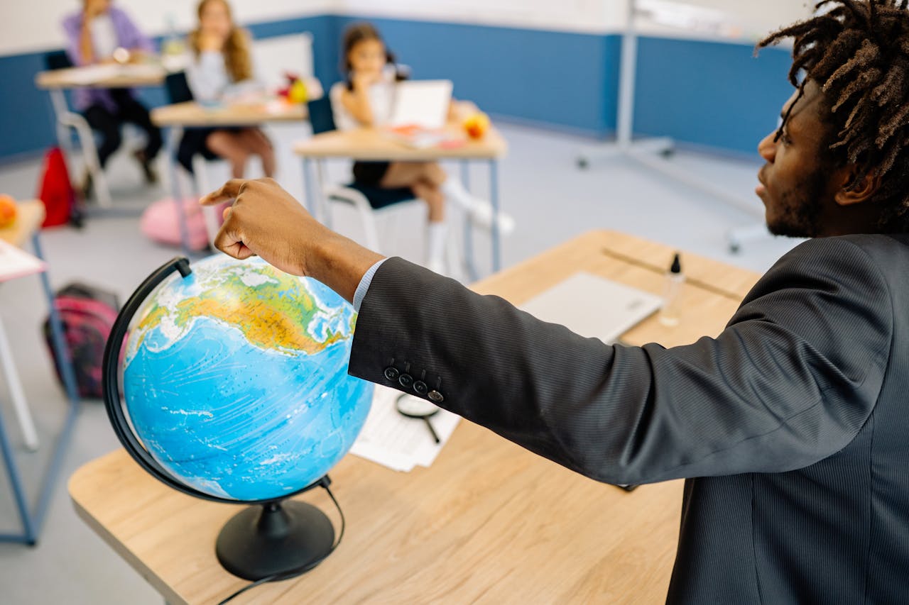 services-01 A teacher points to a globe in a classroom, engaging students in a geography lesson.
